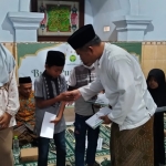 Ketua IKA UINSA Korda Sumenep, Ahmad Rahman, saat menyerahkan santunan kepada anak yatim dalam kegiatan berbagi Ramadan. (Istimewa)