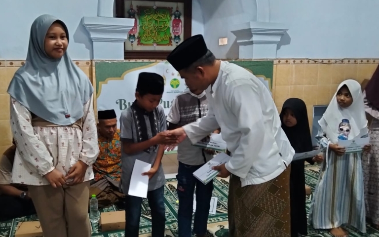 Ketua IKA UINSA Korda Sumenep, Ahmad Rahman, saat menyerahkan santunan kepada anak yatim dalam kegiatan berbagi Ramadan. (Istimewa)